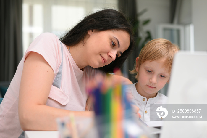 Online courses for preschoolers. 5 years boy uses a laptop at home. Homework with his mother in quarantine at home during covid 19 coronavirus pandemic.