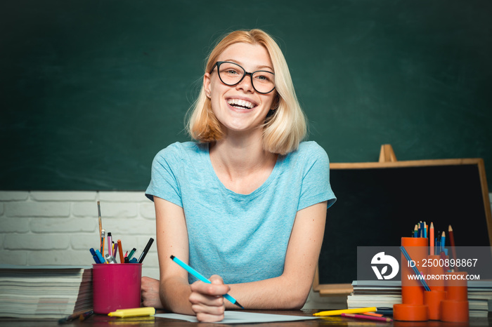 Female student taking notes from a book in college. Student. Portrait of confident young Caucasian female teacher. Student studying in the classroom.