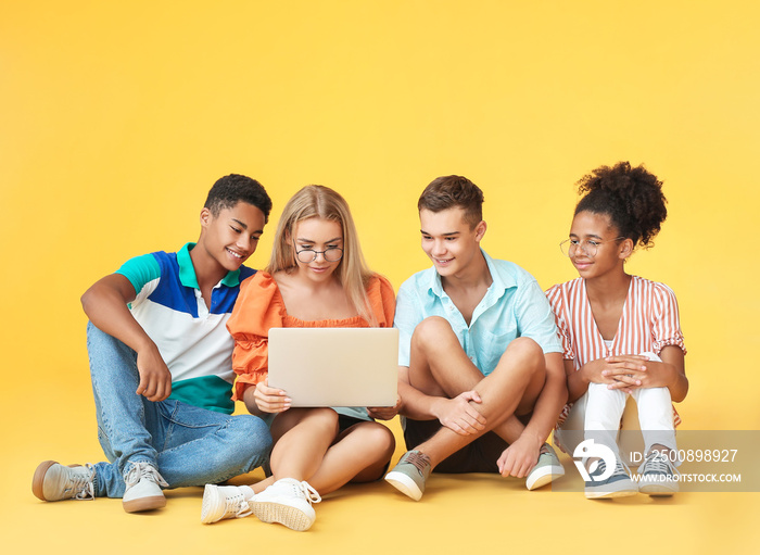 Teenagers with modern laptop on color background