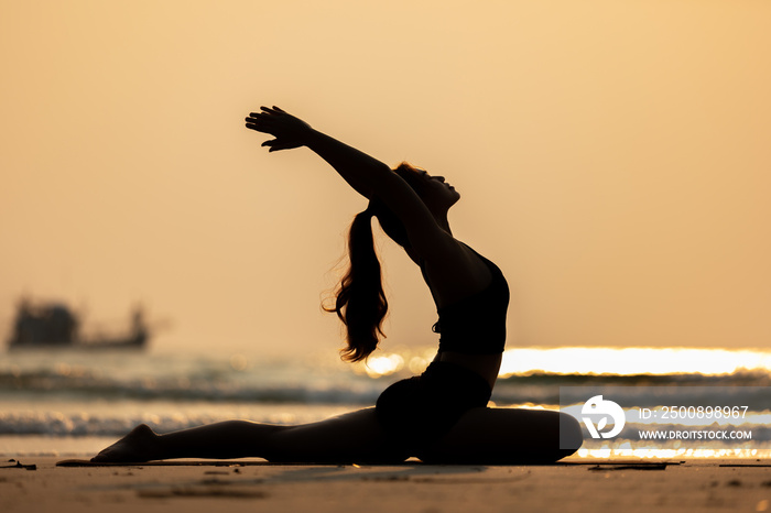 Silhouette Happy Asian woman wearing black sport wear practice yoga Pigeon pose on the beach with beautiful sea in Tropical island,Feeling comfortable and relax in holiday,Vacations Concept