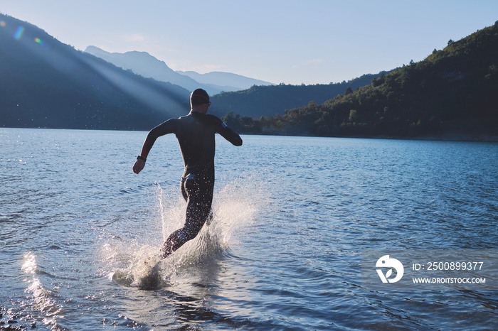 triathlon athlete starting swimming training on lake