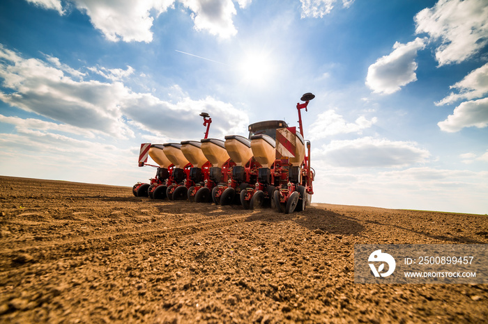 Farmer seeding, sowing crops at field. Sowing is the process of planting seeds in the ground as part of the early spring time agricultural activities.