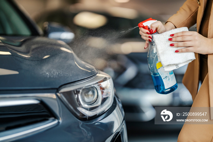 Close up of a car seller cleaning car in car dealership salon.