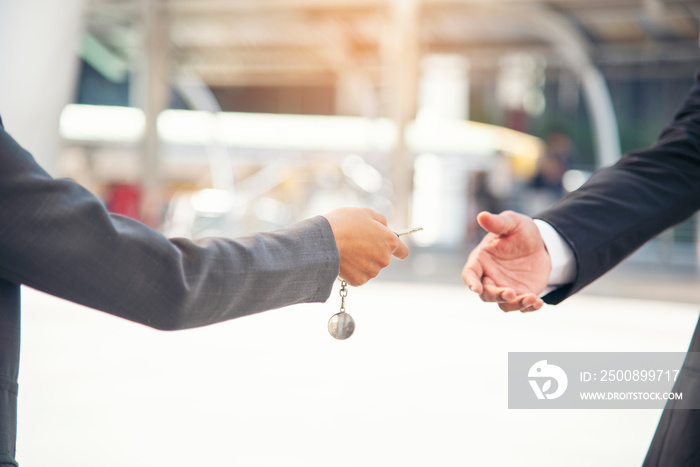 Women Hand give remote control car key to man rental car service. Close up hands of young woman showing new car key to man. Businesswoman hands holding car rental key. Women driver giving car service