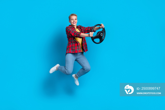 Full body length size photo of short blonde hair woman jump professional rider hold steering wheel practice drive isolated on blue color background