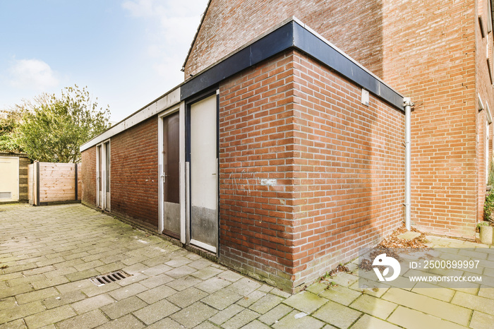 View of the corner of the brick extension with doors in the paved backyard