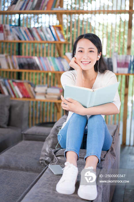 年轻女子在书店看书听音乐