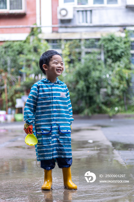 快乐的小男孩雨后在水坑玩耍