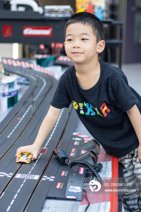 一个小男孩在游戏厅玩赛车玩具