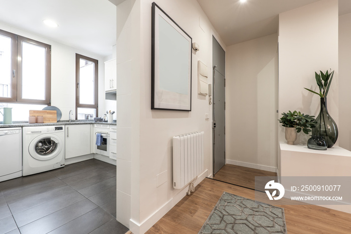 Entrance hall of a house with an open kitchen with white furniture with gray stoneware floors and a 