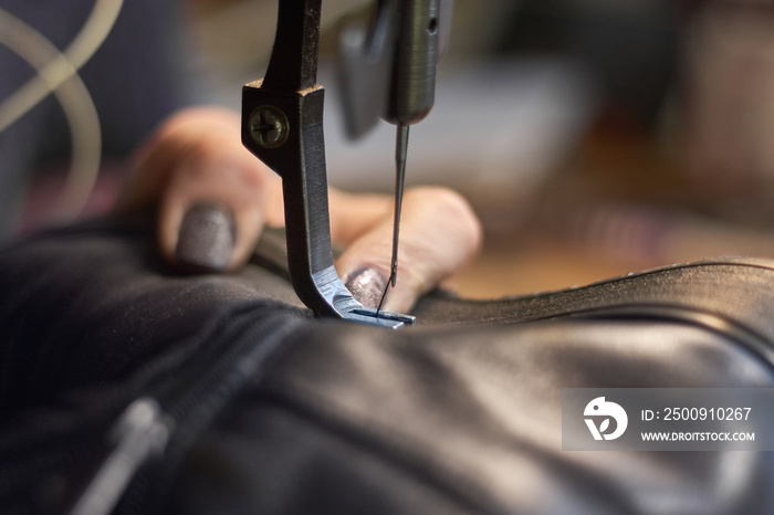 Sewing machine in a leather workshop in action with hands working with a leather details