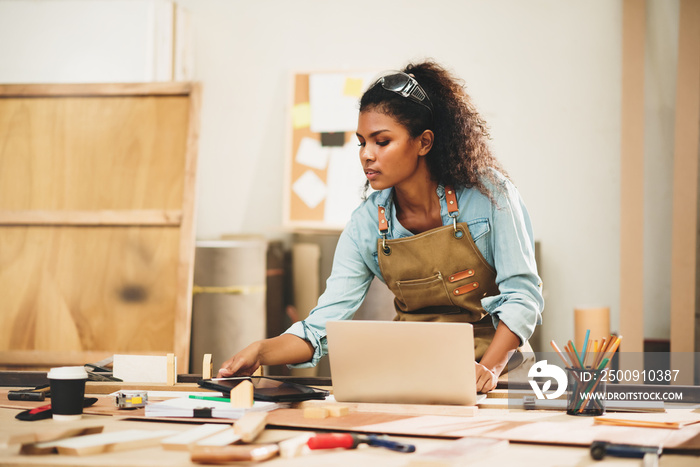 Young attractive african american female carpenter in wood working in small business workshop. Wood 