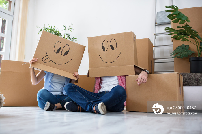 Funny happy couple lying on floor wearing cardboard boxes