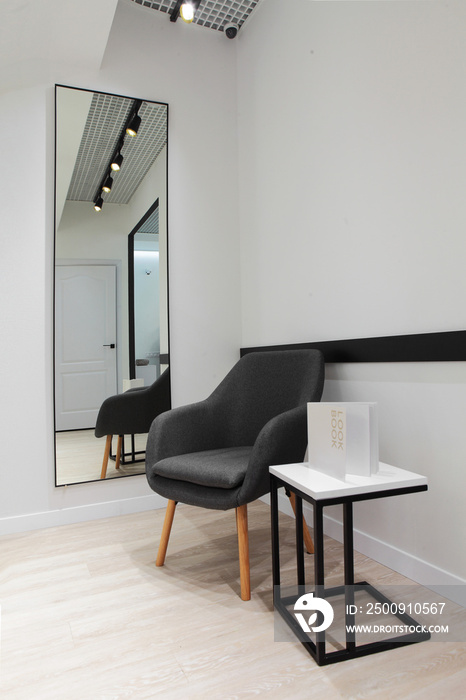 Grey armchair and minimalistic table white and black with metal construction.Book on table with samp