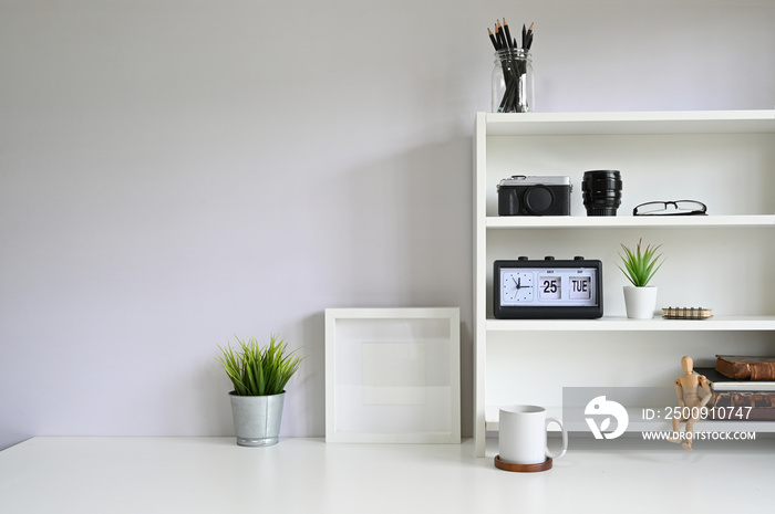 Workspace shelves with camera, lens with photo frame and coffee mug on table.