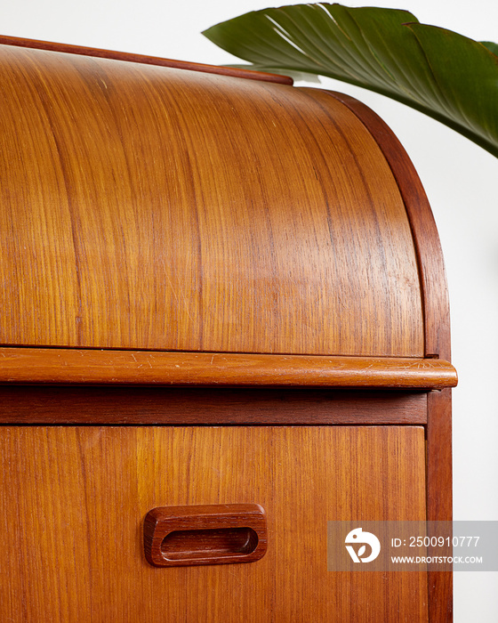 Vintage Mid Century Modern Teak Roll Top Secretary Desk against a white wall