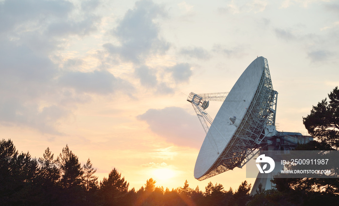 Large radio telescope. Dramatic sunset sky, glowing clouds. Nature, weather, science, equipment, tec