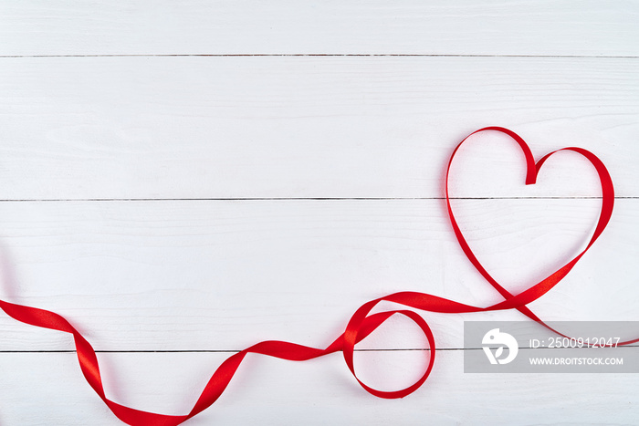 Valentines Day background with red ribbon shaped as heart on white wood table, copy space for text. 