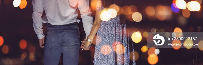 Romantic couple in love holds hands against backdrop of night city lights