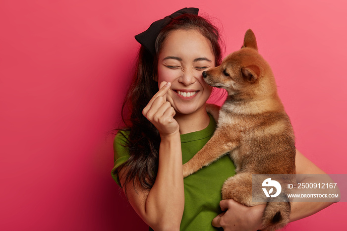 People, love to animals concept. Positive korean girl plays with shiba inu dog, makes mini heart han