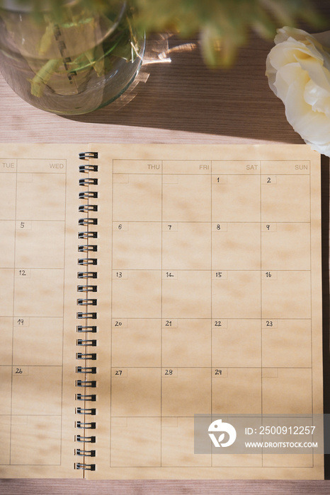 empty message in schedule book of calendar with white rose flower put on table work