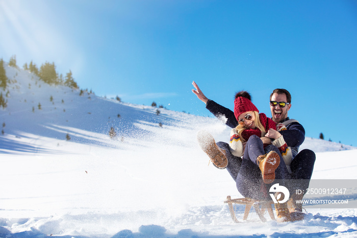 Young Couple Sledding And Enjoying On Sunny Winter Day