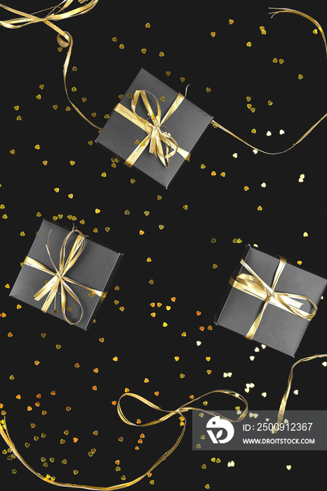 Black gift boxes with gold ribbon on shine background.