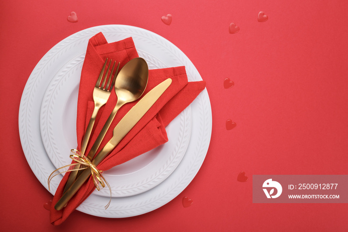 Romantic table setting, gold cutlery on the red table cloth. Valentines day celebration