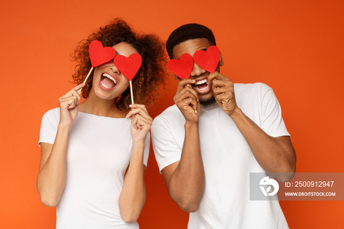 Young couple holding red love hearts over eyes