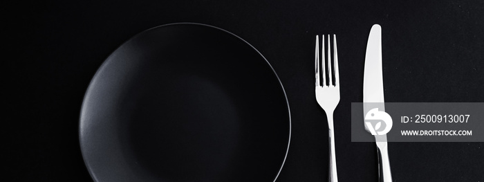 Empty plates and silverware on black background, premium tableware for holiday dinner, minimalistic 