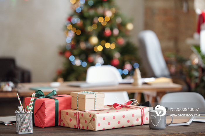 Christmas gifts wrapped into paper and bound with ribbons among office supplies