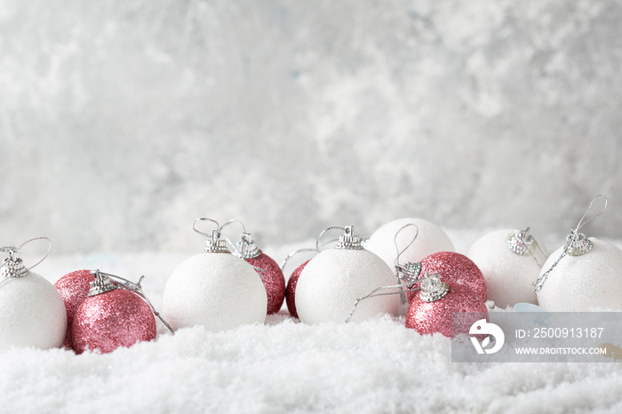 White and pink Christmas tree decorations on snow