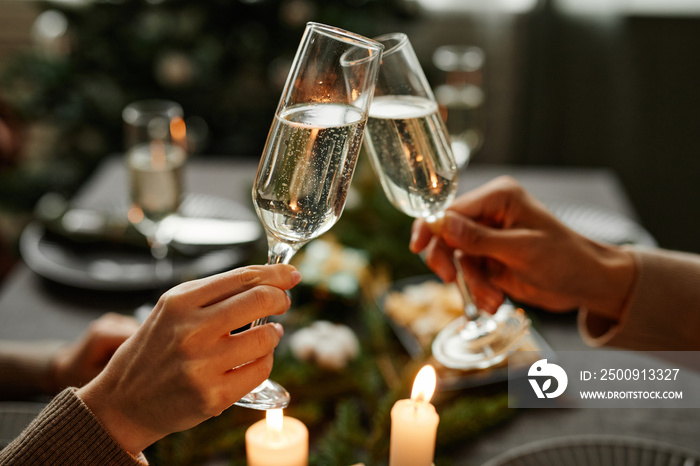 Side view close up of young couple clinking champagne glasses while enjoying Christmas dinner togeth