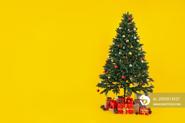 Composition with Christmas tree and gifts on yellow background