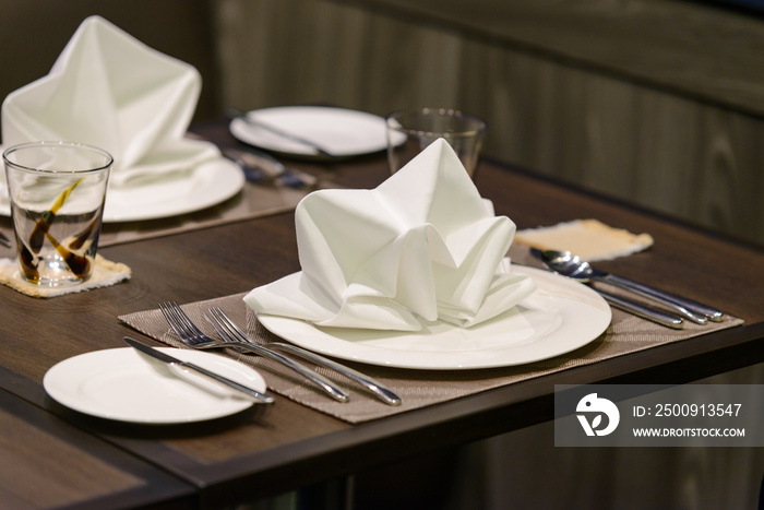 White serviette decorated on dinner set table in restaurant