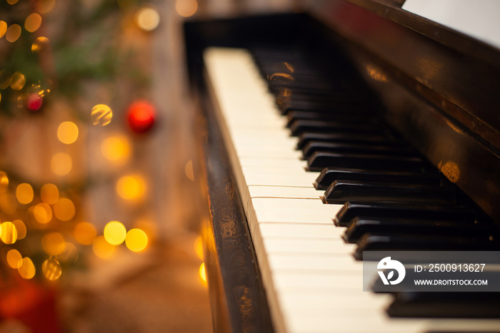 Keys of the piano close up, festive Christmas decoration and lights on the background. Entertainment