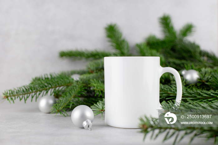 Blank white mug mockup with christmas tree branches and silver balls on light concrete stone backgro