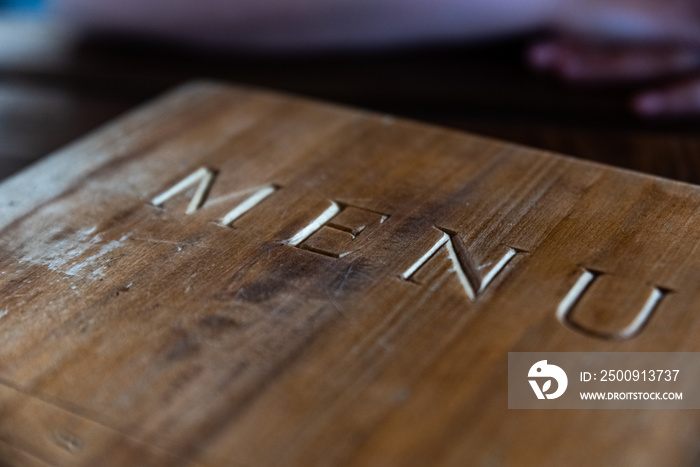 Wooden cover of the menu card with the inscription. Scratched and damaged brown retro board.