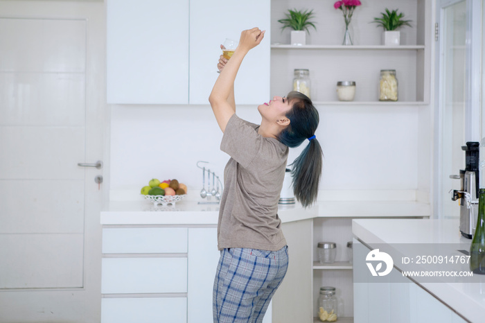 Drunk Asian woman dancing in the kitchen