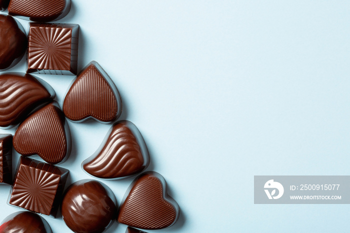 Chocolate pralines assortment on blue background, flat lay, top view with copy space