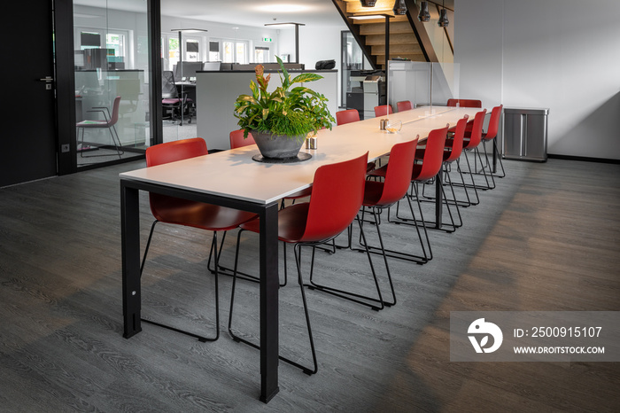 long dining table with red chairs in an office building.