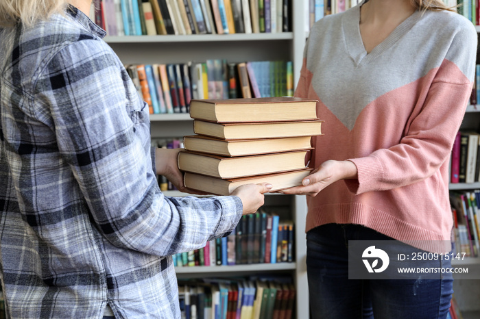 Young woman receiving books from librarian