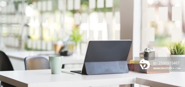 Cropped shot of modern office room with blank screen tablet, camera and office supplies