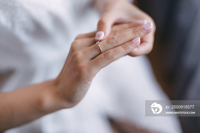 Close-up of a gold ring with a diamond on the brides hand with a delicate manicure.