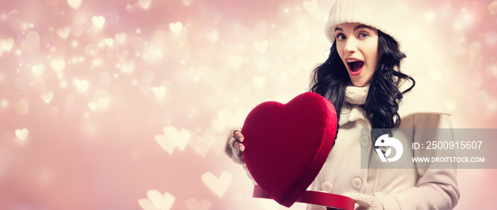 Happy young woman holding a big heart gift box