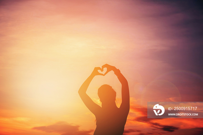 Women hands forming a heart with sunset silhouette