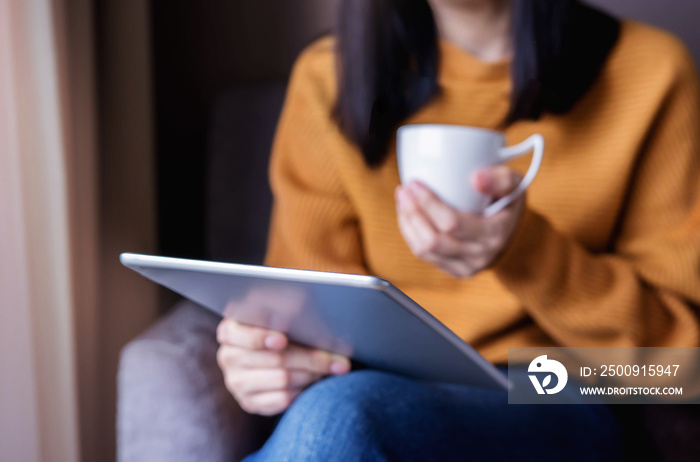 Reading Concept. Young Woman using Tablet and Drinking Coffee. Relaxing in Cozy House, Sit on the Ch