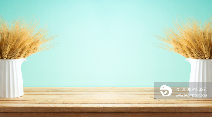 Wheat in vase on wooden table over blue background. Shavuot holiday decor mock up for design.