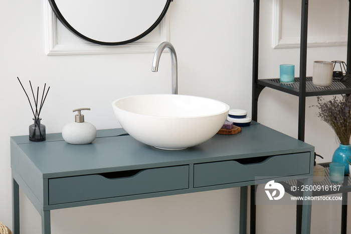 Interior of bathroom with sink, table and shelving unit