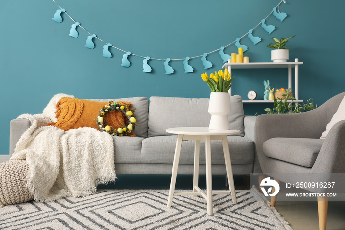 Interior of living room with Easter wreath, paper rabbits and sofa